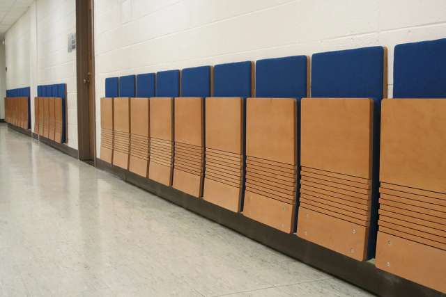 Wall-mounted folding cantilever chair with an engineered wood seat.