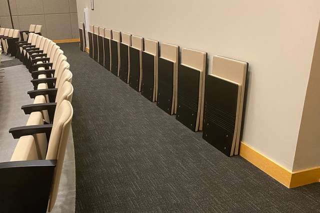 Floor-mounted folding chair with an engineered wood seat and back on a cantilevered frame.