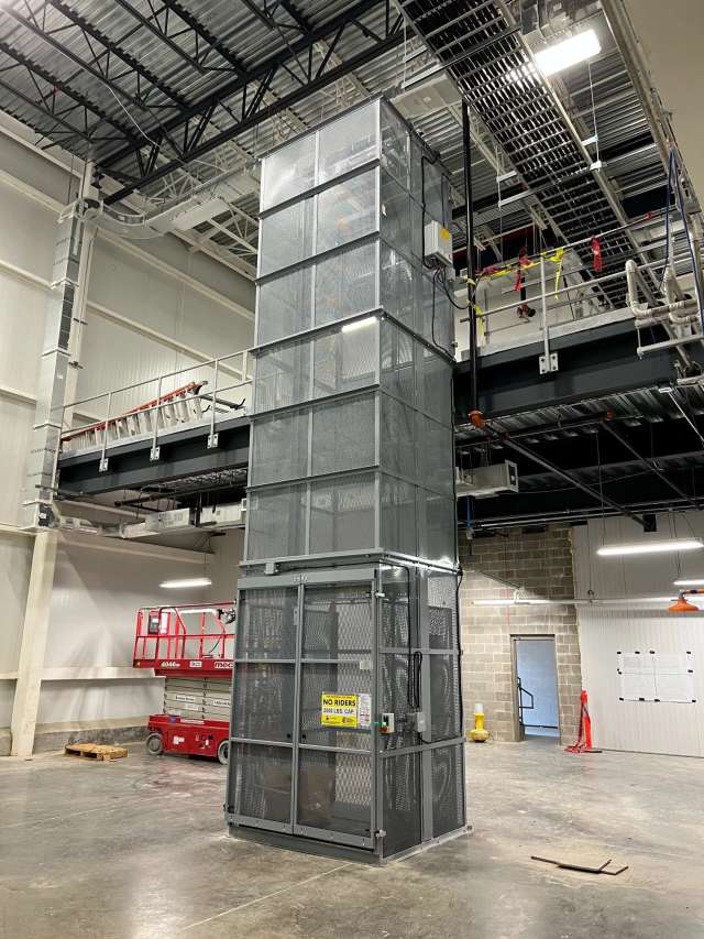 Material handling vertical reciprocating conveyor for lifting loads between levels.