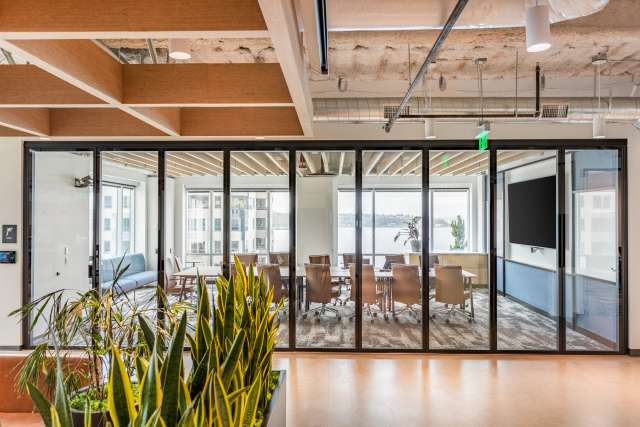 Glass folding panel partition with continuous hinges in a conference room.