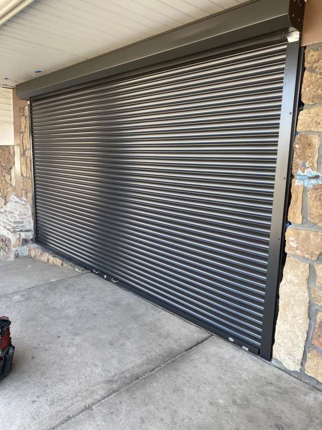 Outdoor security shutter with interlocking metal slats and a reinforced frame.