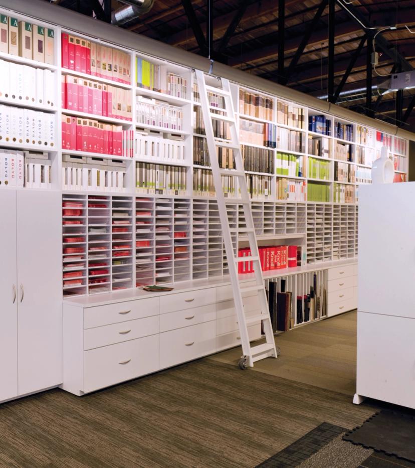 Floor-to-ceiling white modular casework with a rolling ladder in a design library