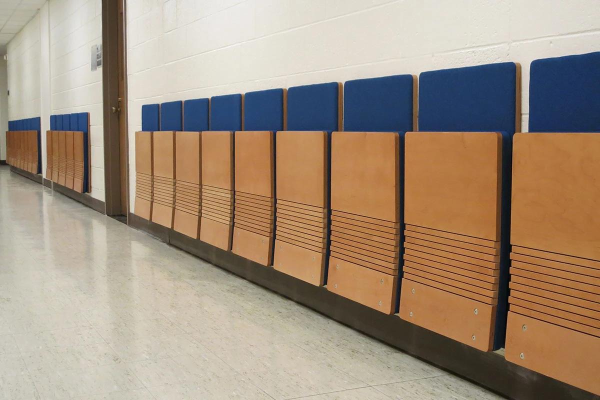 Wall-mounted folding cantilever chair with an engineered wood seat.