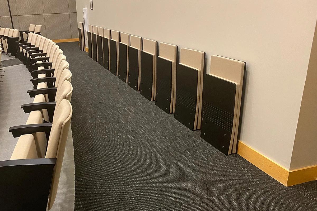 Floor-mounted folding chair with an engineered wood seat and back on a cantilevered frame.