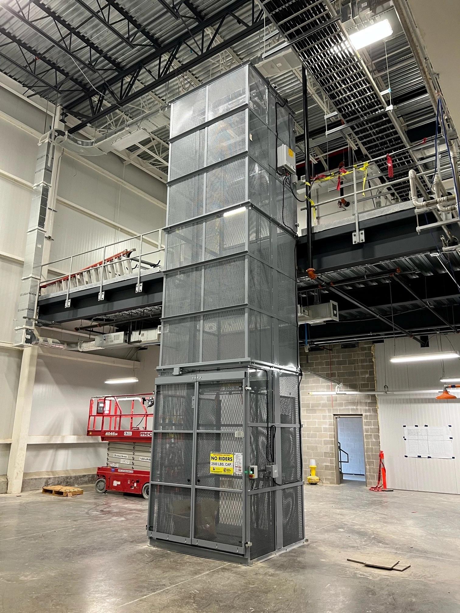 Material handling vertical reciprocating conveyor for lifting loads between levels.